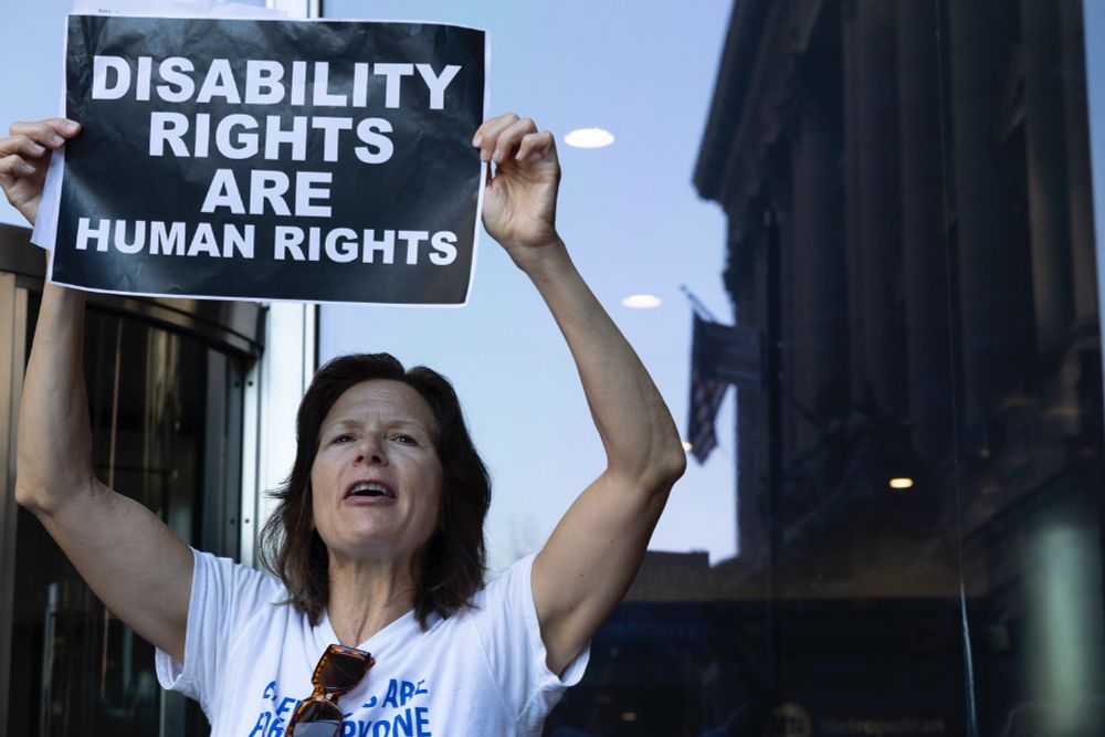 A photo of an activist holding a poster that reads Disability Rights are Human Rights