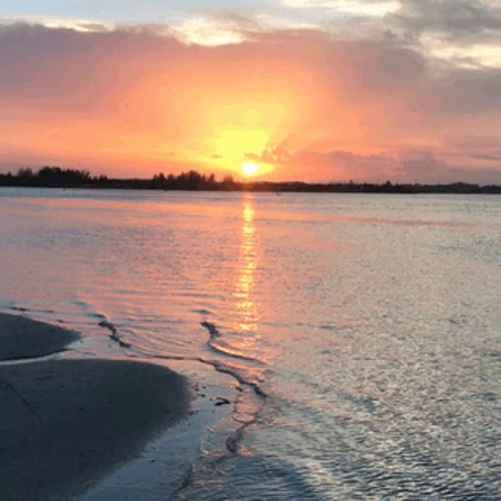 a sunset over a body of water with the sun shining through the clouds