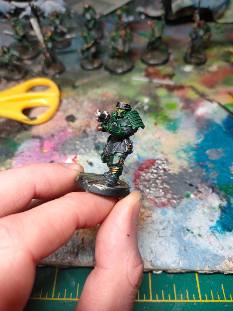 A Necromunda enforcer painted green wearing a bandana and carrying a pistol 