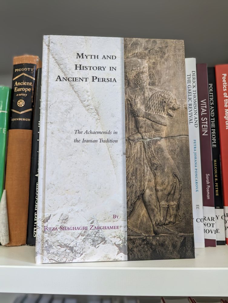 Photo of a hardback book, Myth and History in Ancient Persia by Reza Shaghaghi Zarghamee. The cover shows a carved figure holding a lion.