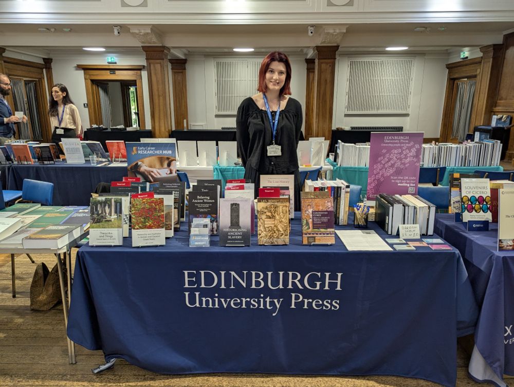 A photo of the Edinburgh University Press book stall, Helena Heald stands behind it.