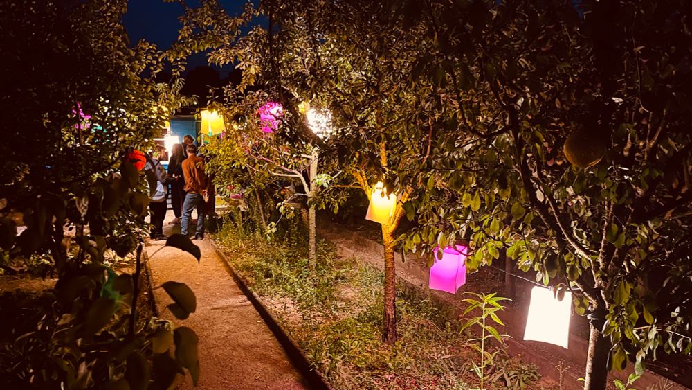 Es ist nun fast dunkel. Lampions hängen in Obstbäumen. Davor ein Schmaler Weg