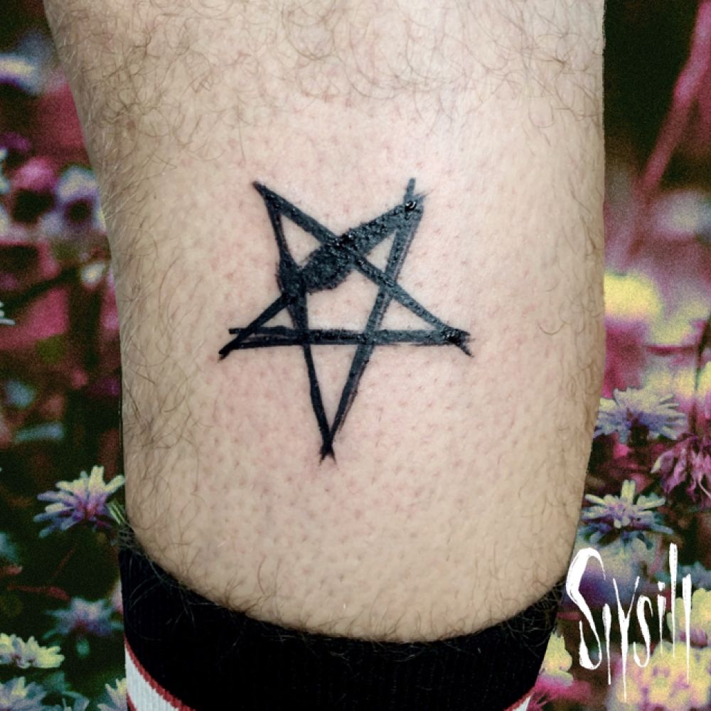 Tatouage d’un pentagramme graphique en noir sur le mollet. Fond floral 90’s