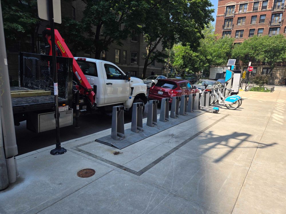 New Divvy station on wide sidewalk with crane truck behind it and installation wrapping up