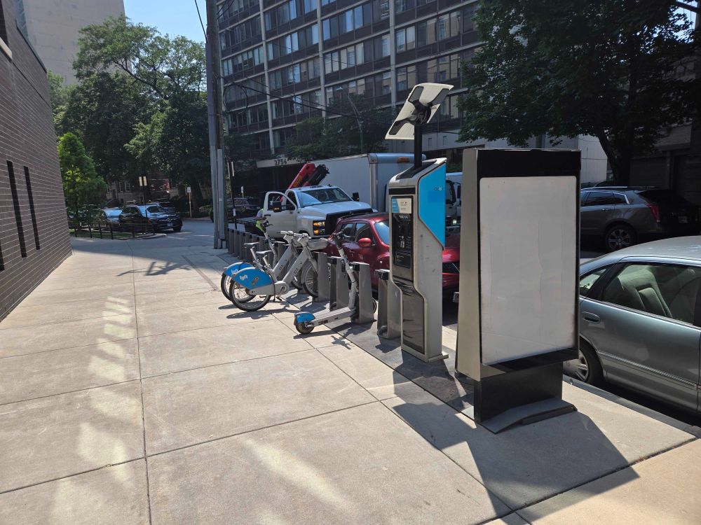 New Divvy station on wide sidewalk with crane truck behind it and installation wrapping up