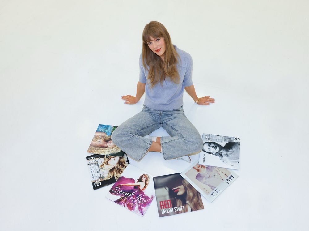 Taylor Swift surrounded by the vinyls of her first six records.