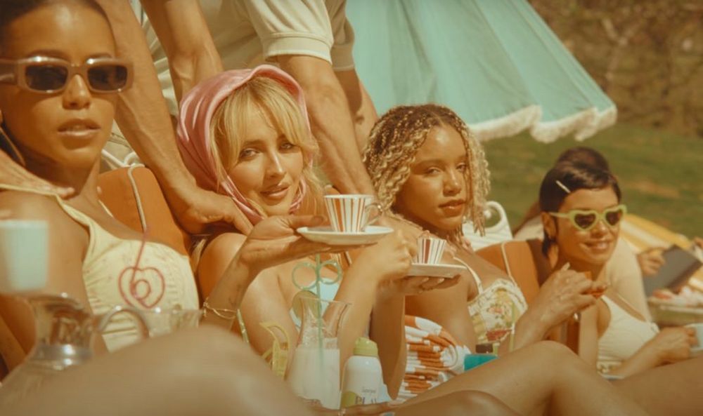 Photo of Sabrina Carpenter in the ‘Espresso’ music video surrounded by women holding teacups. 