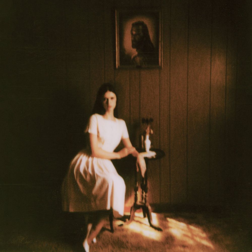 Ethel Cain sitting on a chair for the ‘Preacher’s Daughter’ album cover. 