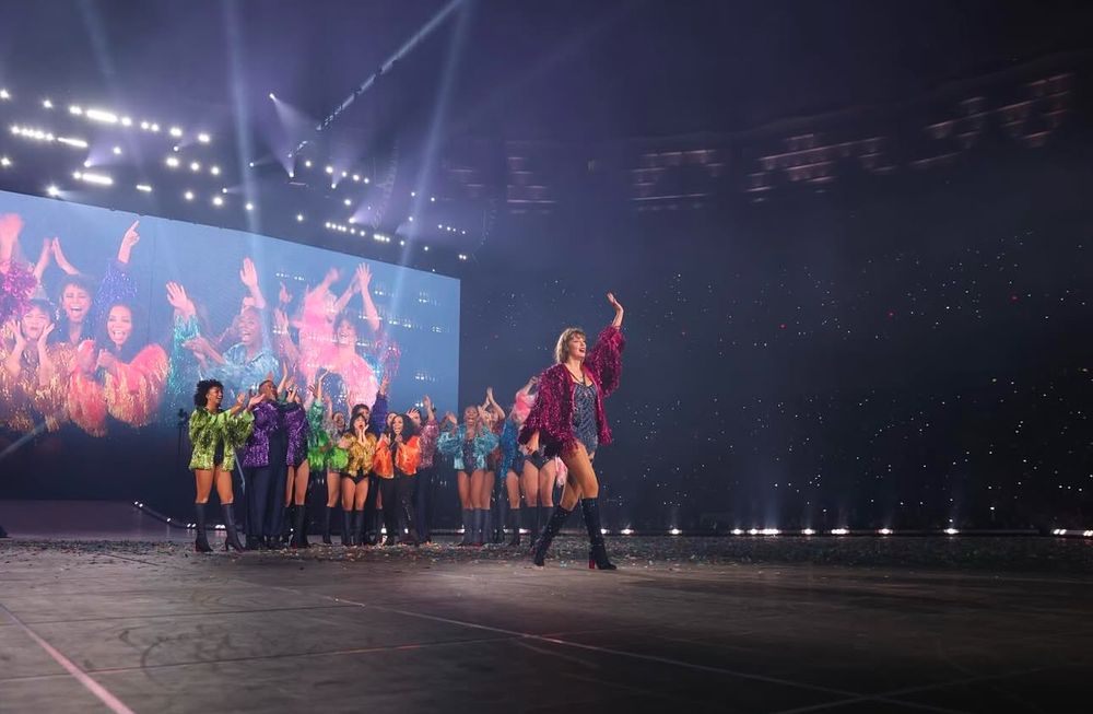 Taylor Swift waving goodbye to the Eras Tour along with her crew. 