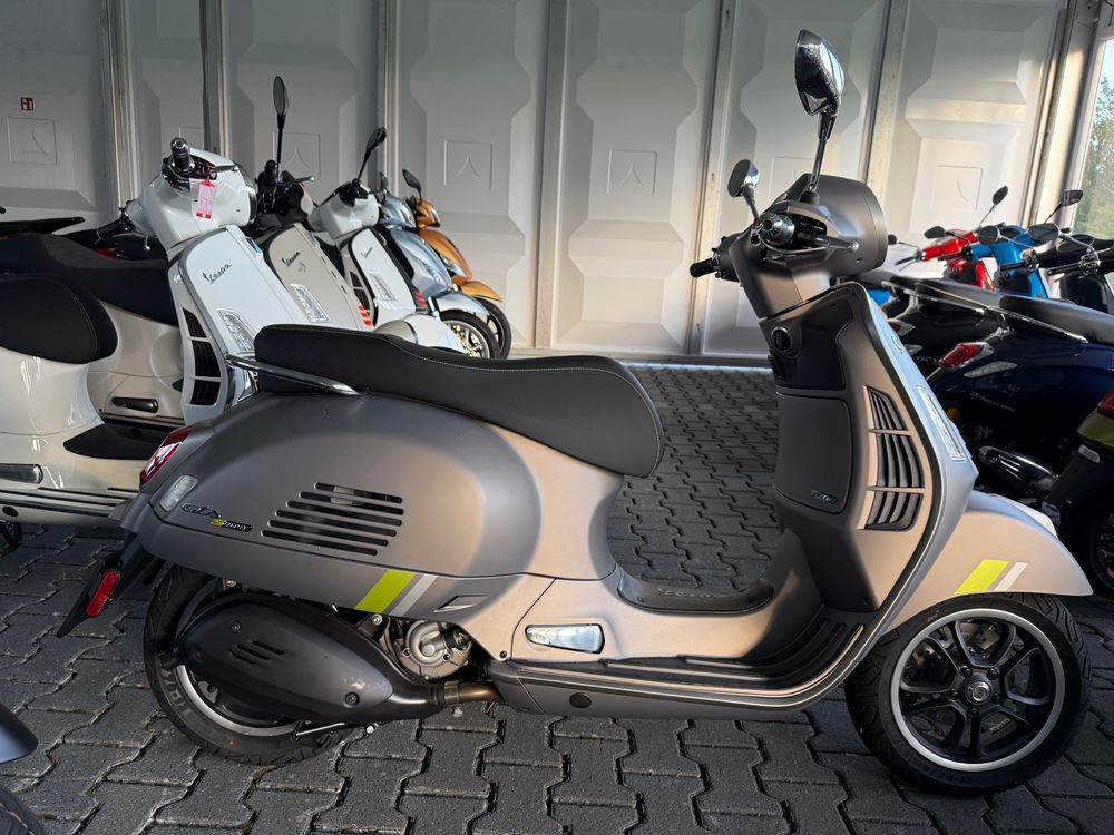 Eine Mattgraue Vespa 300 GTS Supertech .
Im Hintergrund mehrere Vespas in verschiedenen Farben 