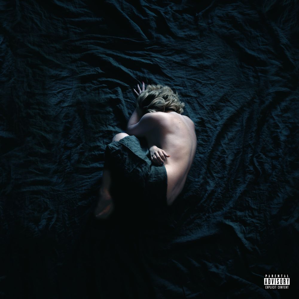 Singer JoJo curled in a ball in the middle of a black sheet