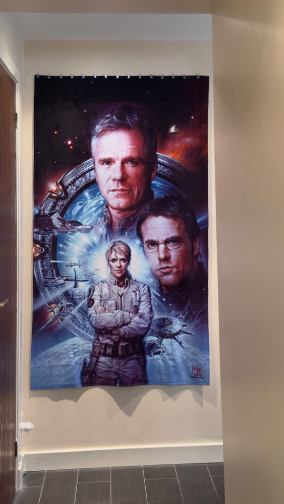 Souvenir beach towel from FedCon33, with Stargate SG1 characters Jack O’Neill, Sam Carter and Daniel Jackson against a Stargate space background.