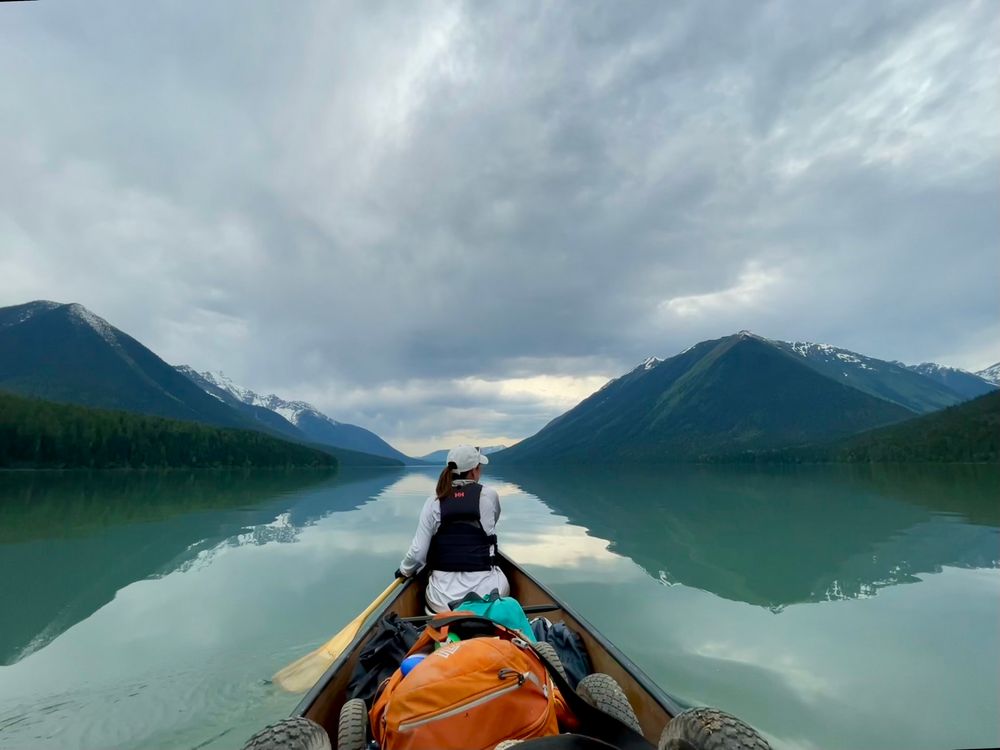 Canoe on Isaac Lake. Mountains reflected in still water
