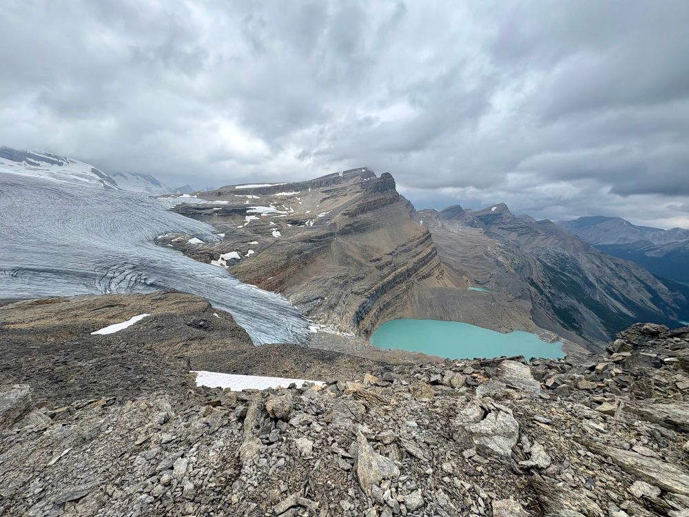 A glacier on the left with a glacial lake below in aqua. 