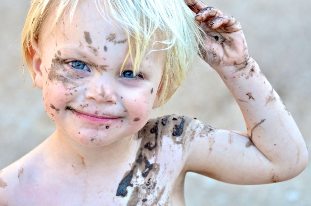 A kid playing in mud - they're absolutely covered, and seemingly quite pleased about it!