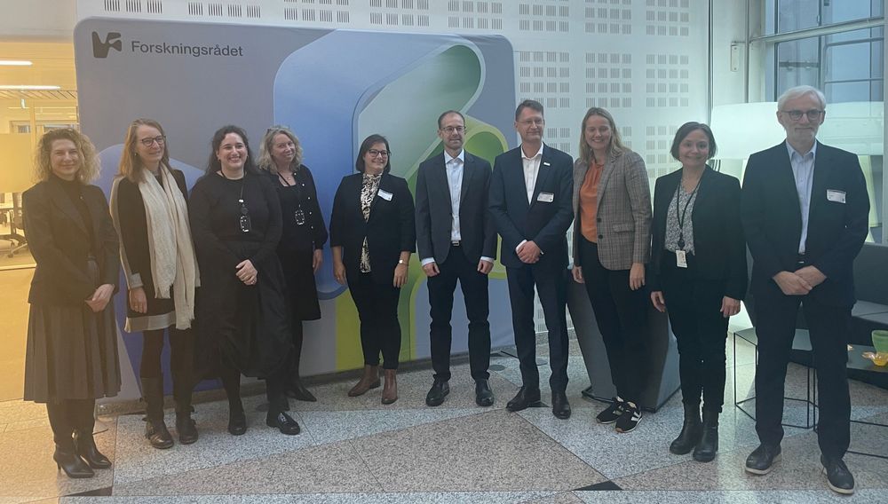 Group of 10 men and women standing in front of a company sign in a lobby