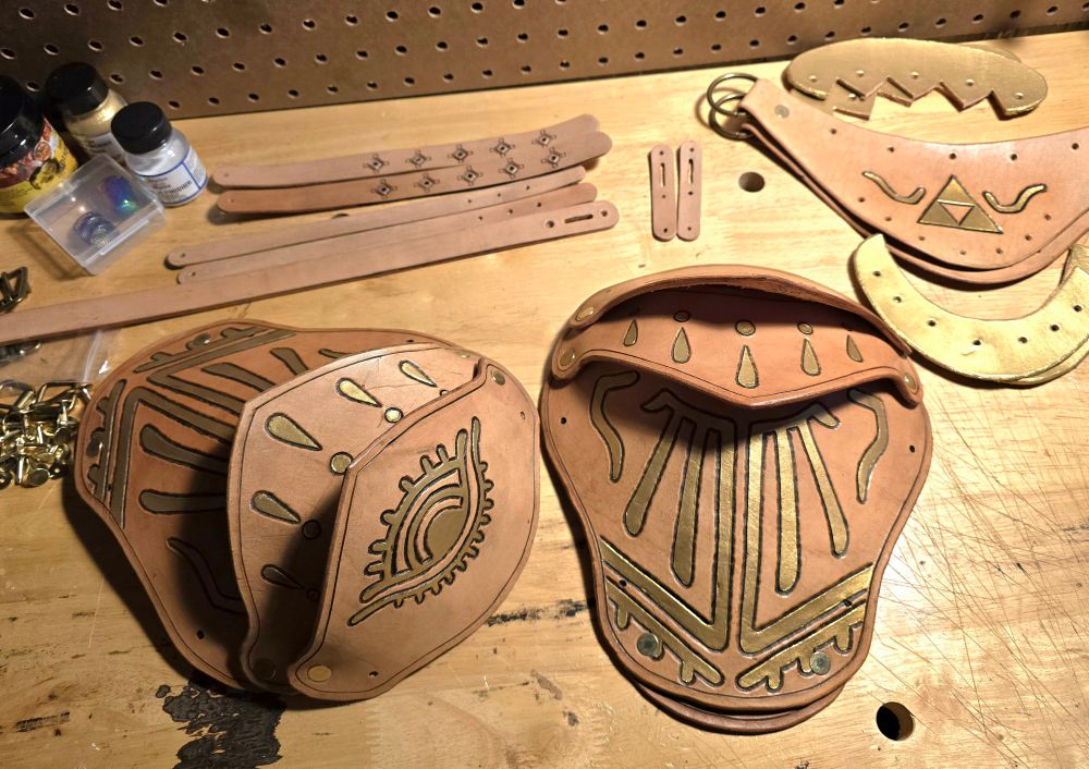 Leather pauldron armor pieces with hand stamped and gold-painted designs based off the newer Zelda games. 