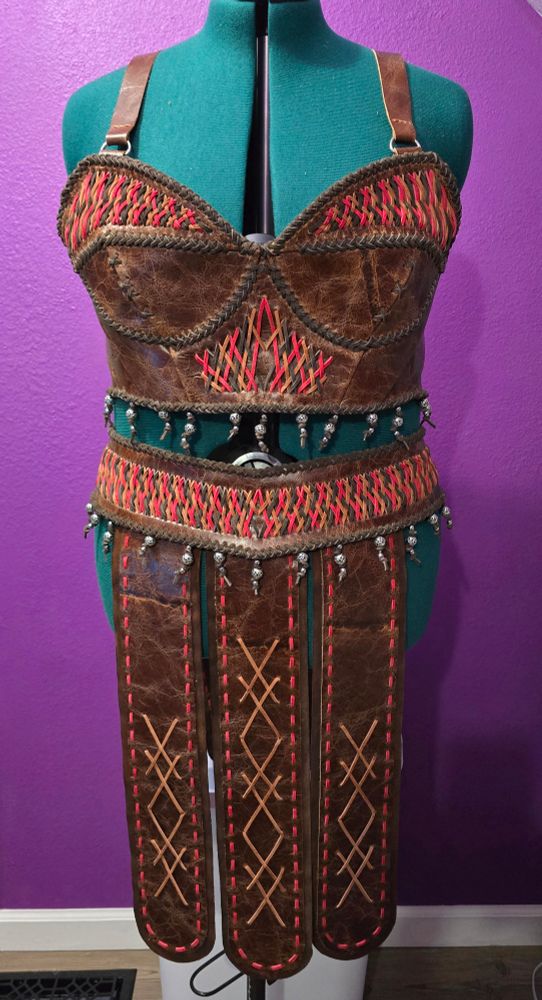 Full leather bustier and skirt with hand woven leather details in brown, tan, and red.