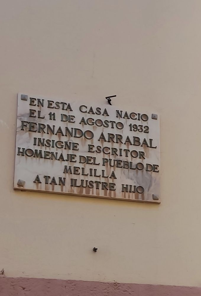 Placa de mármol en una fachada que dice: "En esta casa nació el 11 de agosto de 1932 Fernando Arrabal, insigne escritor. Homenaje del pueblo de Melilla a tan insigne hijo". Muy insigne placa, diría yo.