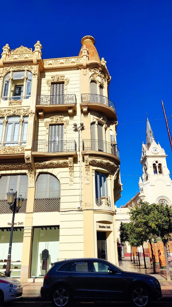 Un edificio de estilo modernista melillense, con la fachada muy decorada, amplios ventanales y una cúpula.