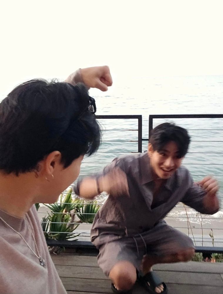 i actually don't know whats going on in this photo...its literally vmin captured in their natural state lmao its slightly blurred, taehyung is crouched down in the process of raising his arms while laughing, jimin is looking at him so we only see the side of his face and he has....a fist raised? bro idk its vmin okay they be doing whateva 