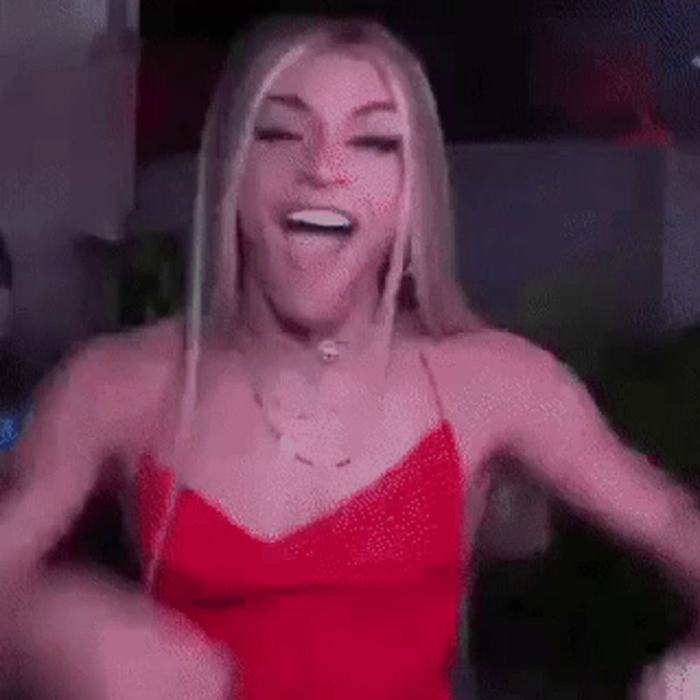 a woman in a red dress is dancing and making a face .