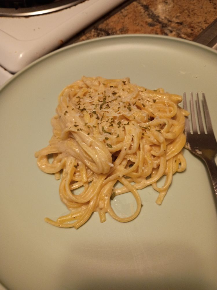 linguine pasta on a light blue plate garnished with parmesan and parsley