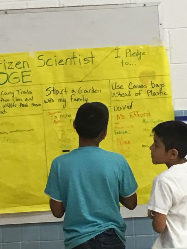 Two elementary students identifying a citizen scientist project they are planning and will implement 