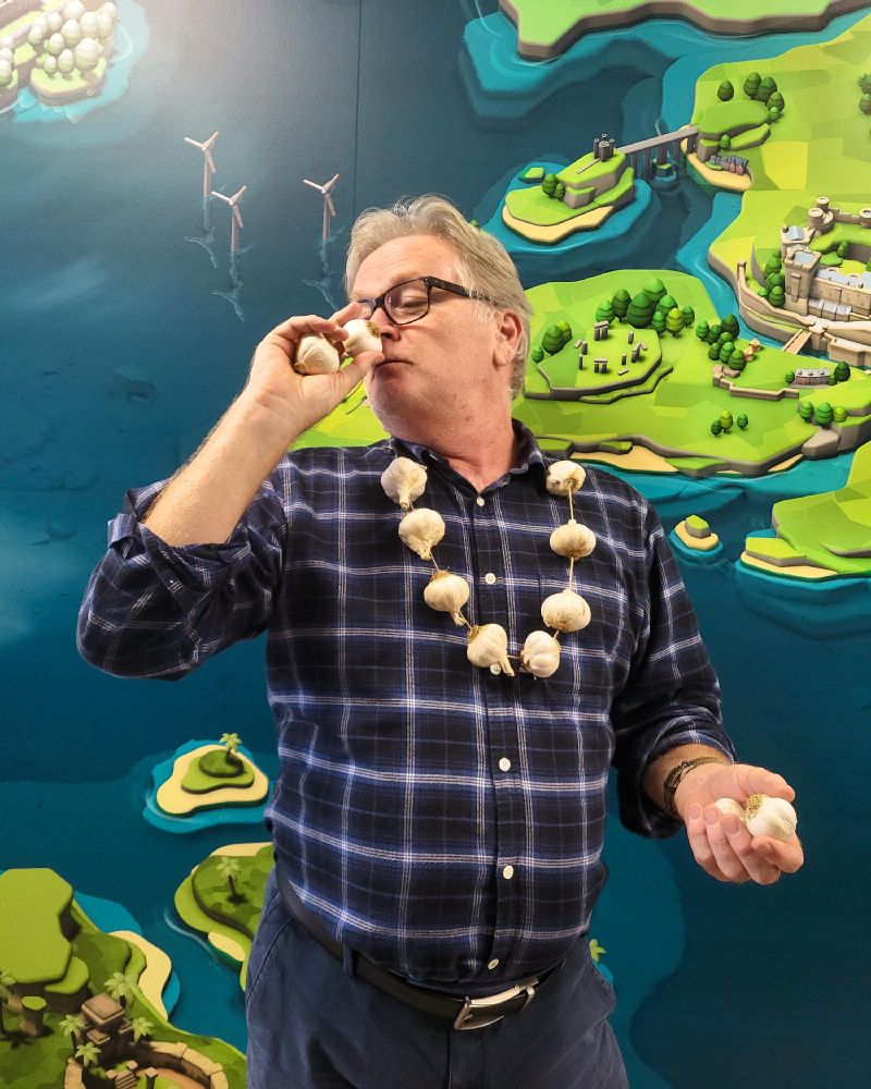 Two Point legend Mark Webley wearing a garland made of garlic, holding two more garlic bulbs in each hand.