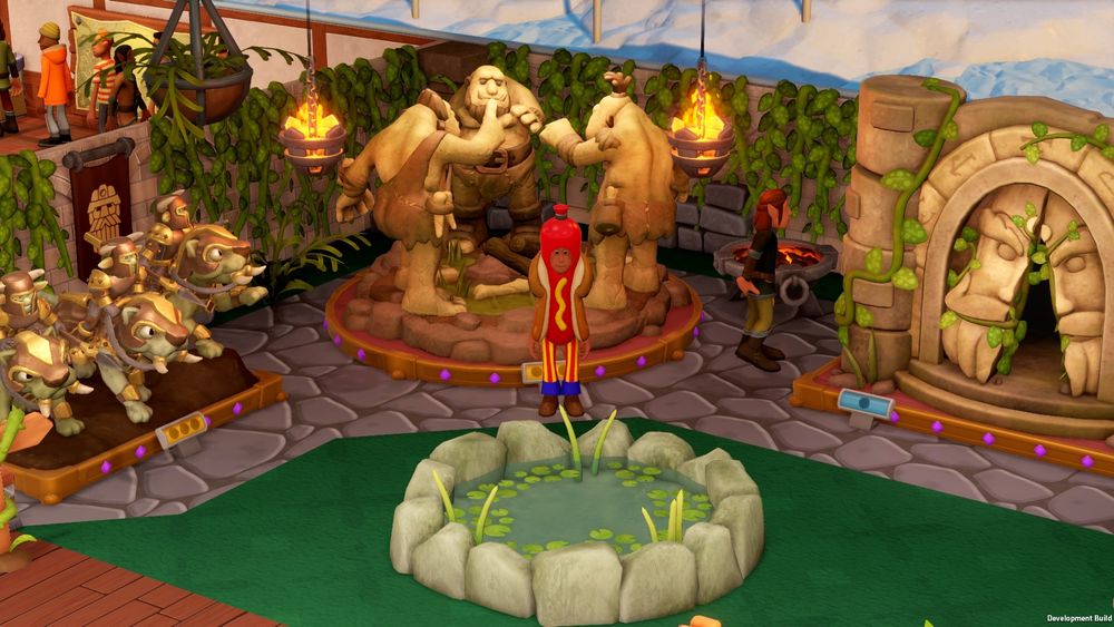 Screenshot from Two Point Museum of a staff member wearing a giant hotdog costume, which is a big contrast to their environment. They're surrounded by pretty, fantasy nature themed statues.