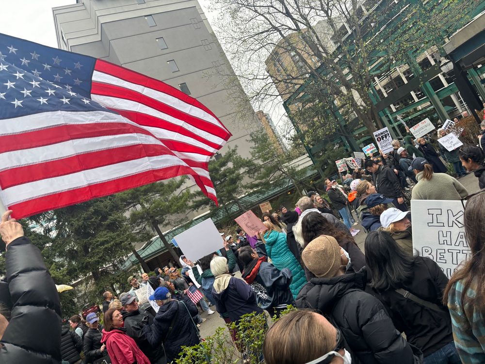 Multiple people at a protest with an American flag in the foreground