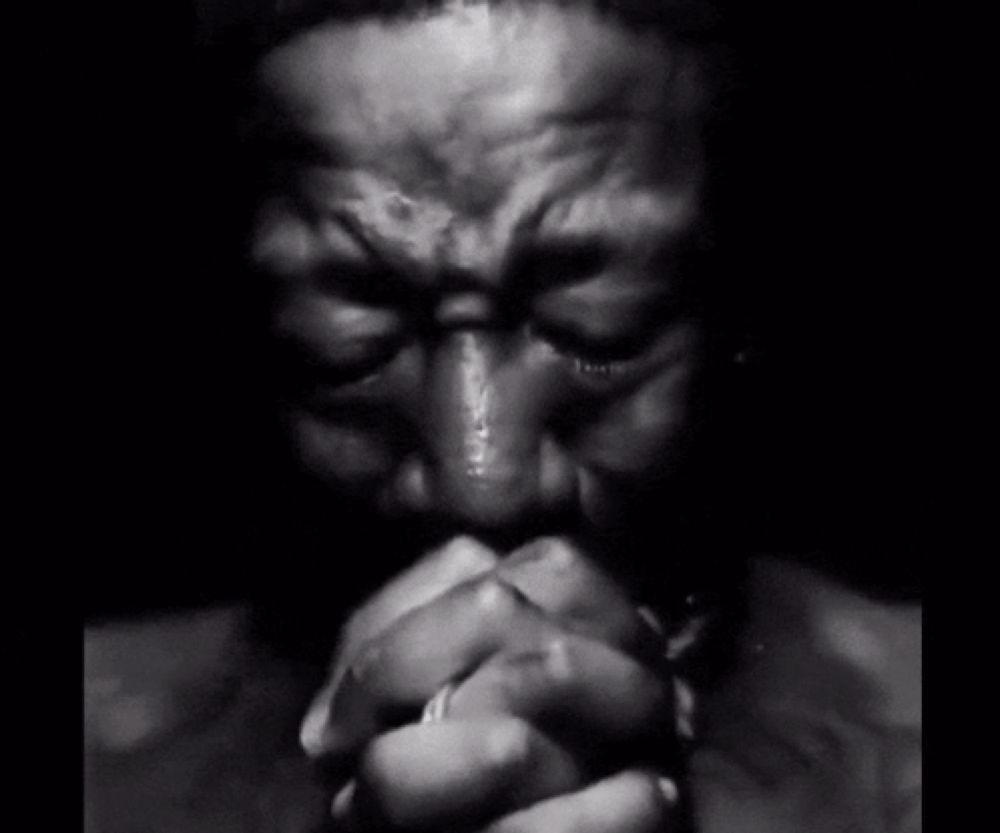 a black and white photo of a man covering his mouth with his hands