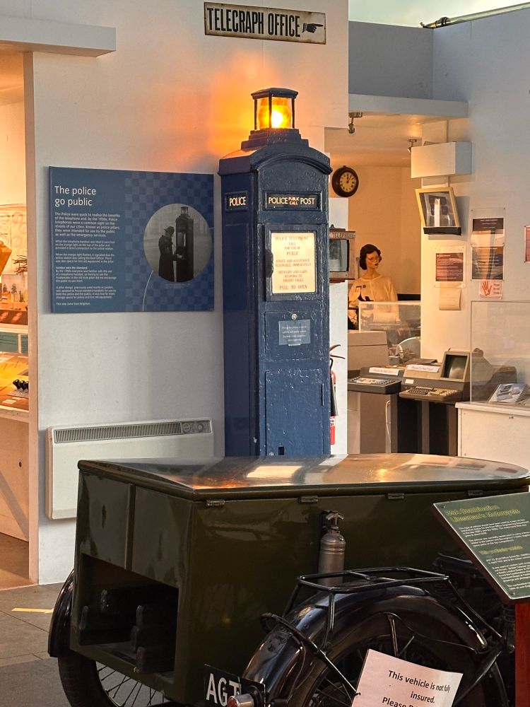 A blue police telephone box with the yellow light lit up