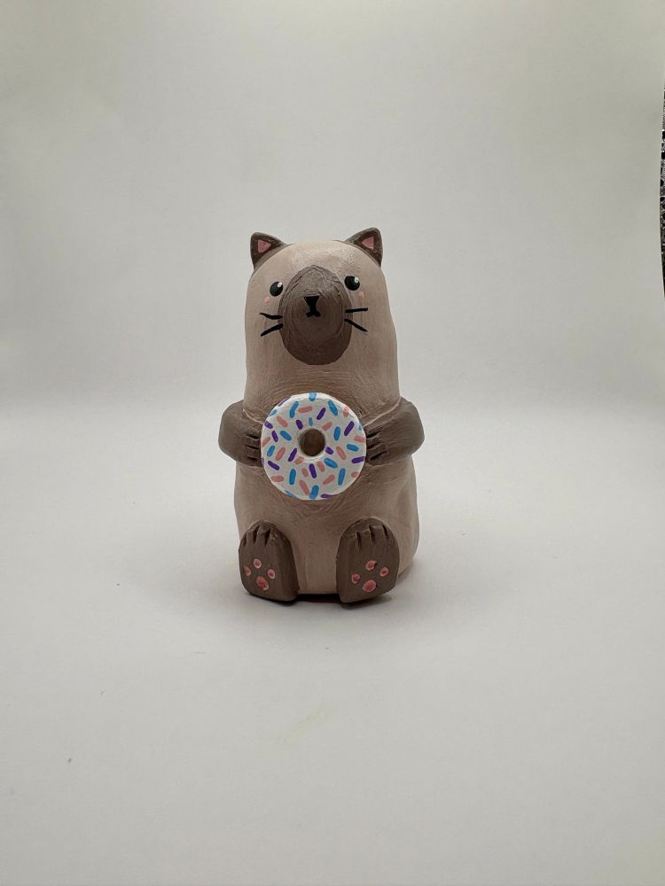 Siamese cat made of clay holding a donut