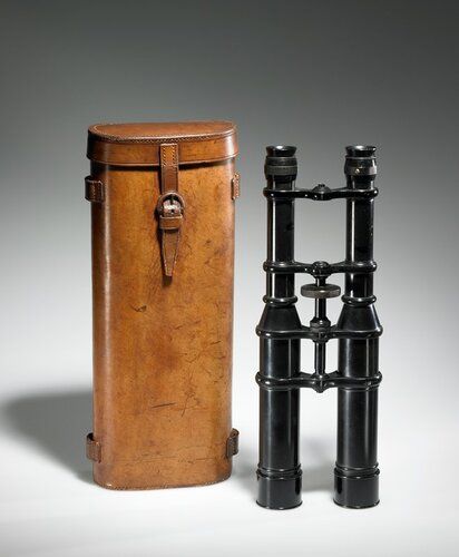 long; black metal; leather case with buckle closure included
Binoculars are not a new instrument--early European records record their development in the 17th century--but the "binocular Micro-Telescope" combined the magnifcation of a telescope with stereoscopic vision in one well-made instrument. Essentially two telescopes mounted together, it promised good field, definition, depth of focus, and remarkable perspective. A reviewer advised using the lower magnification of 14 until necessary to add the higher magnification eyepieces that upped the performance to 22 and 28 maginfication. High-performance with or without a stand, for landscape views or stargazing, they were the type of “field glasses” used during World War I. The central large ring is for adjusting overall focus, while the eye pieces can be adjusted individually.