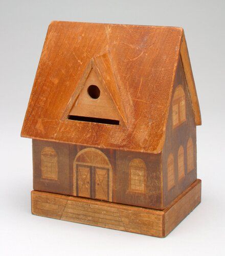 house dark brown; roof reddish brown, light brown dormer with hole on front and back roof; dark brown outlined double front door with painted dark brown handle; lines on doors create four triangles, half circle window above front door; eight sketched light brown multipaned windows with half circle above; front two, sides three each, double windows each side; base dark brown lines create bricks, steps in front; coin slot below front dormer