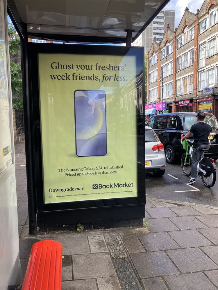 An ad at a bus stop for a company that refurbishes phones. 