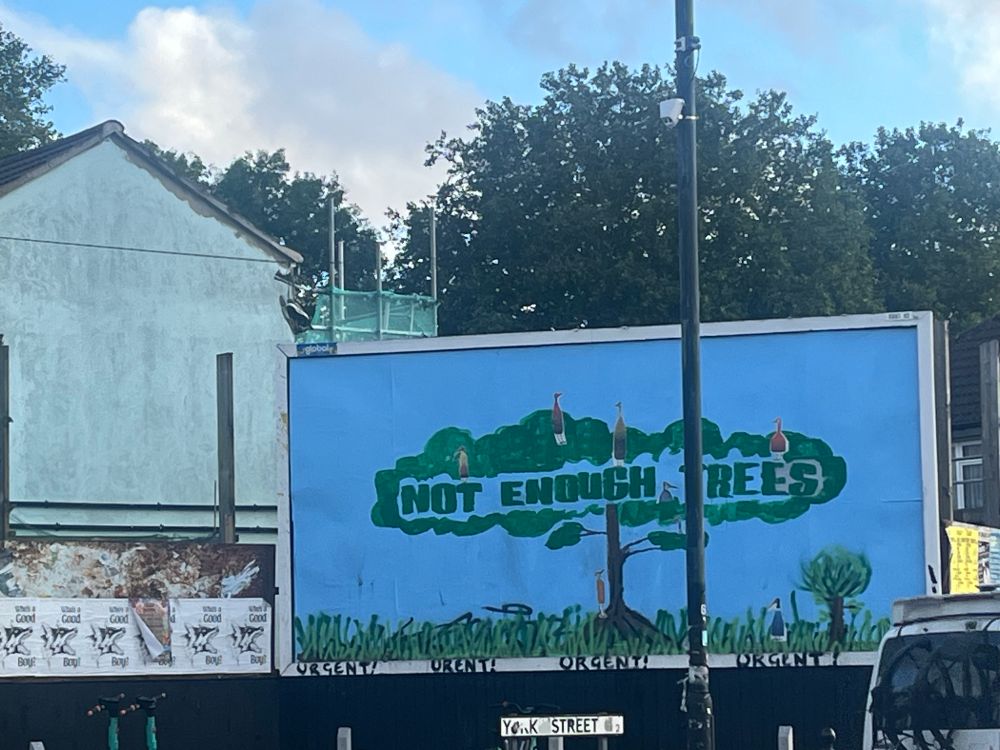 Billboard poster on street with painted tree and the slogan “Not enough trees”. 