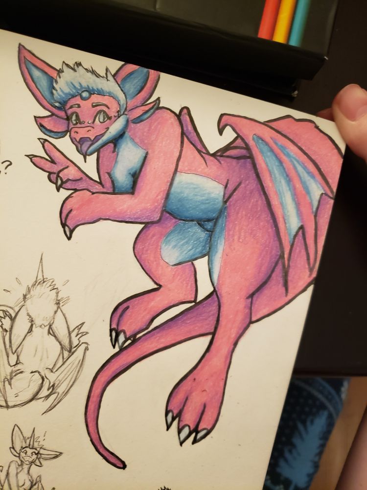 Traditional ink and colored pencil drawing of Ralphie, a pink anthro dragon. They are unclothed, but their chest and genitals are tastefully covered in their pose. They are hovering in a bent position on the top-right corner of the sketchbook page, legs and tail dangling as if in flight. Their torso leans out to the left, and they're smiling playfully at the viewer with their tongue out while holding up two fingers on one hand. 