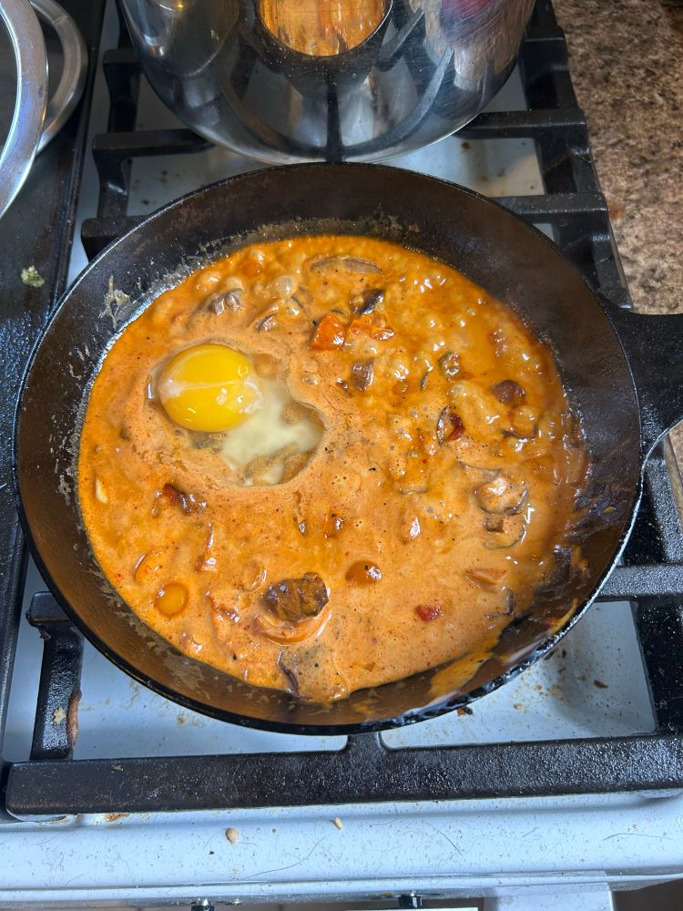 A cast iron pan with curry and an egg poaching