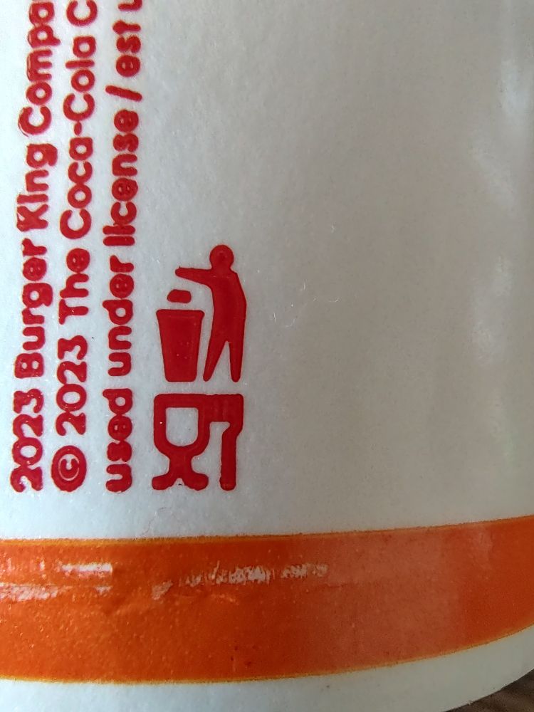 Imagin on a Burger King cup meant to show that the cup and plastic utensils should be thrown away, but it looks like one person shoving another person feet first into a toilet.