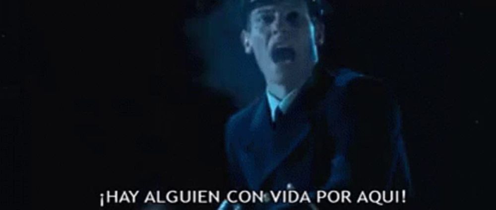 a man in a suit and tie is screaming in a dark room in spanish .