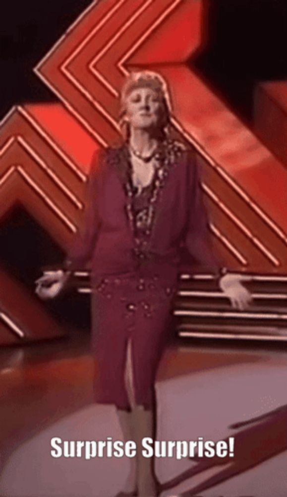 a woman in a purple dress is standing on a stage with the words surprise surprise written on the bottom