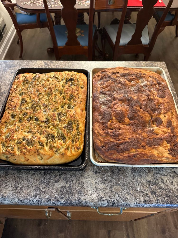 A garlic rosemary focaccia and cinnamon sugar focaccia cool on a counter next to each other 