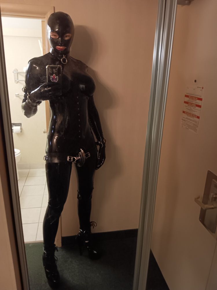 Mirror shot of the poster in full latex and high heeled boots.