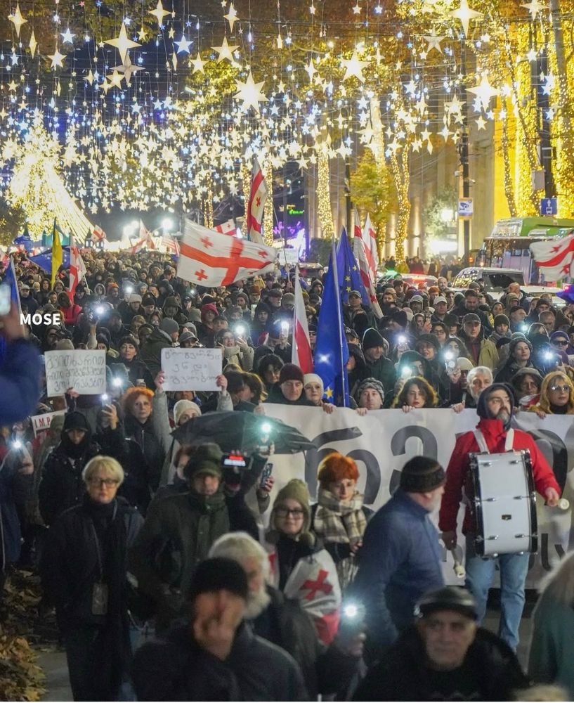 Protesters crowd under new-year decorations and lights
