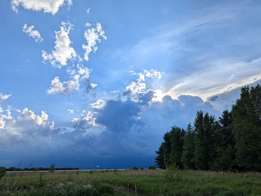 The sun peeking out from behind clouds in a blue sky.