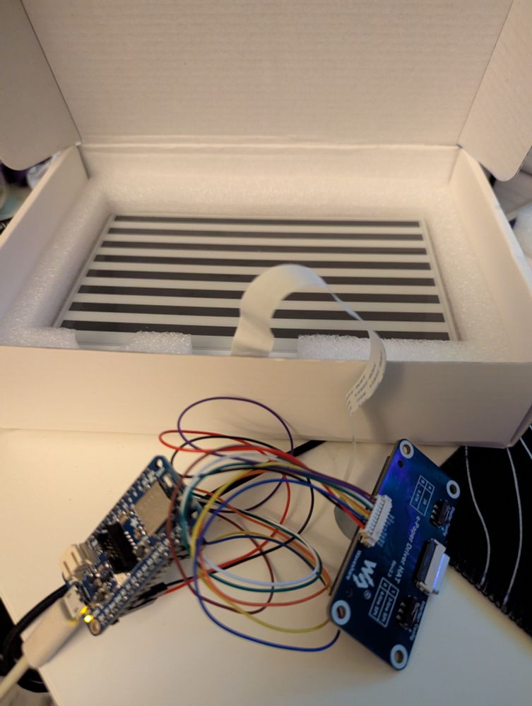 An Adafruit nRF52840 microcontroller board connected to a 7.5" e-ink display, currently showing a stripe test pattern. 