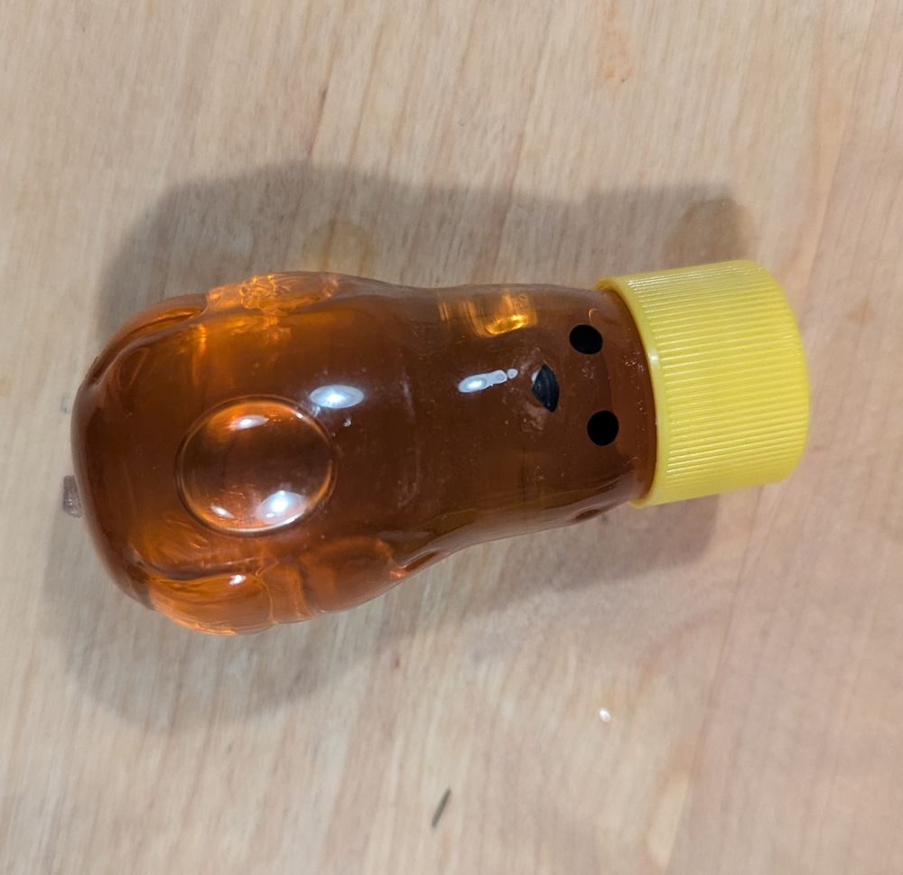 A small plastic honey bear that is bulged and deformed from warm honey. 