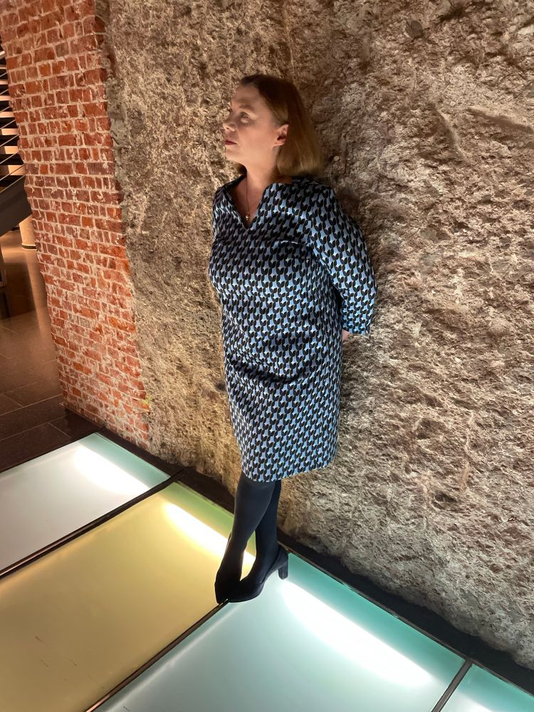 Foto von Alexandra, die an einer Wand aus grobem Stein lehnt